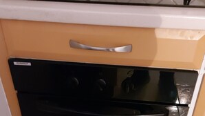 Une cuisine compacte avec un four noir, une seule poignée en acier inoxydable et un tapis à rayures sur le sol.