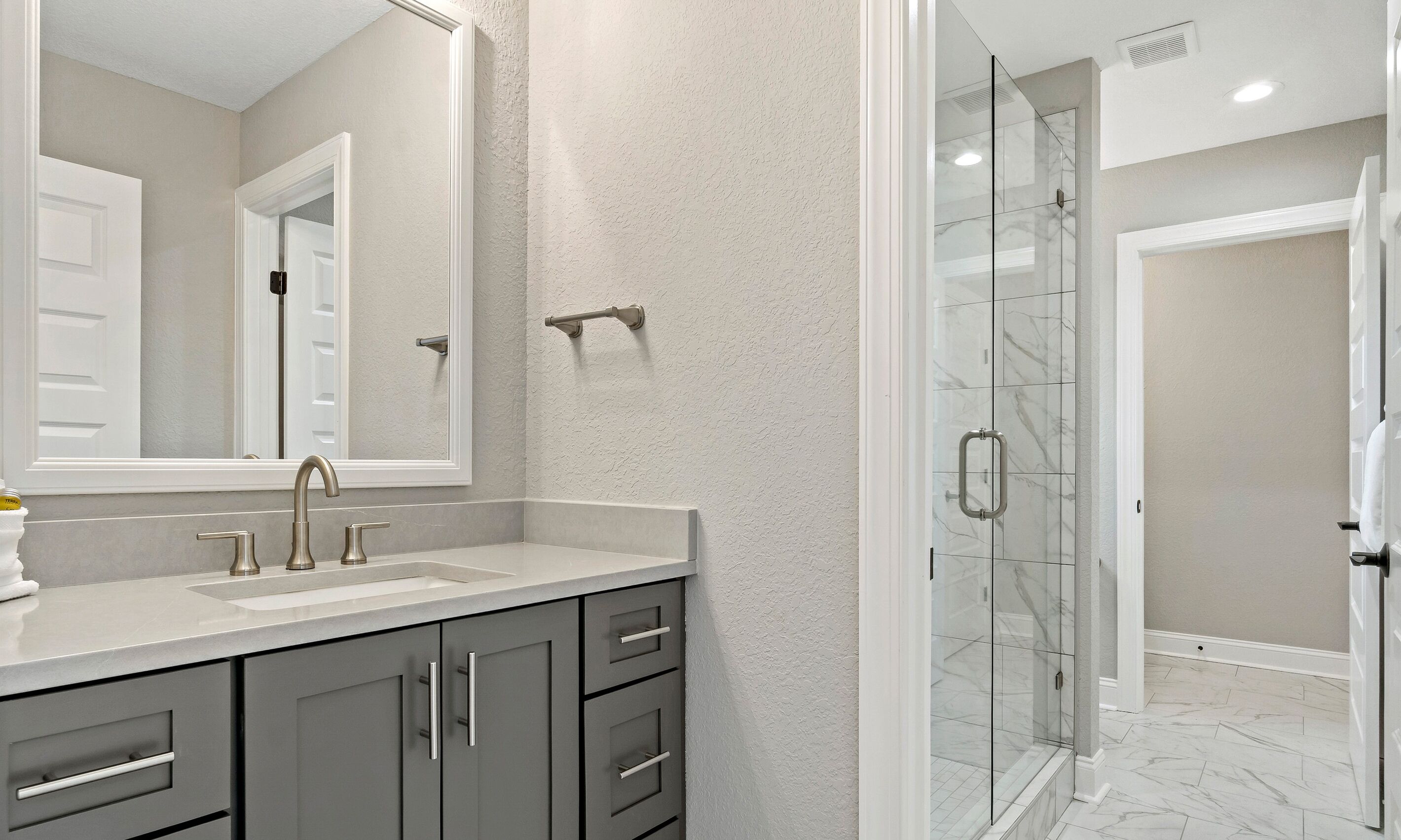 Un baño con lavamanos doble, un espejo grande y cabina de ducha de cristal.