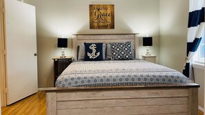 A bedroom with a wooden bed, a ceiling fan, a wall-mounted sign, and a window with curtains.
