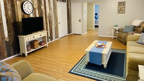 A living room with a wooden wall, a clock, a ceiling fan, and a sofa.