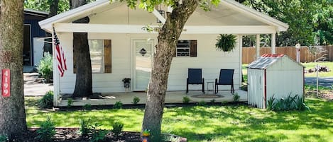 A single-story house with a covered porch, a small shed, and a well-maintained lawn.