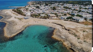 An aerial view of a coastal residential area with houses along the shoreline and a clear blue sea. - The lily vacation home  (Marina di Mancaversa)