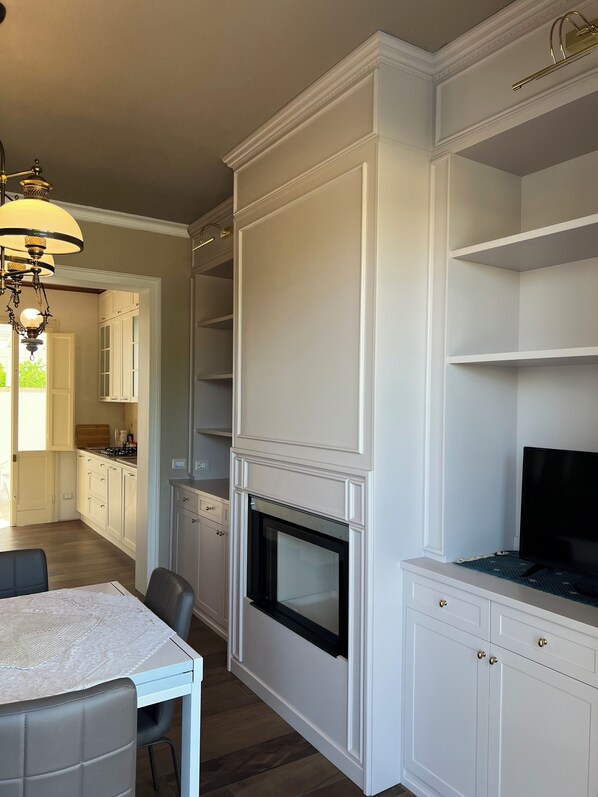 A modern kitchen with white cabinetry, a built-in oven, and a dining area with a table and chairs. - The Lily Vacation Home (Marina di Mancaversa)