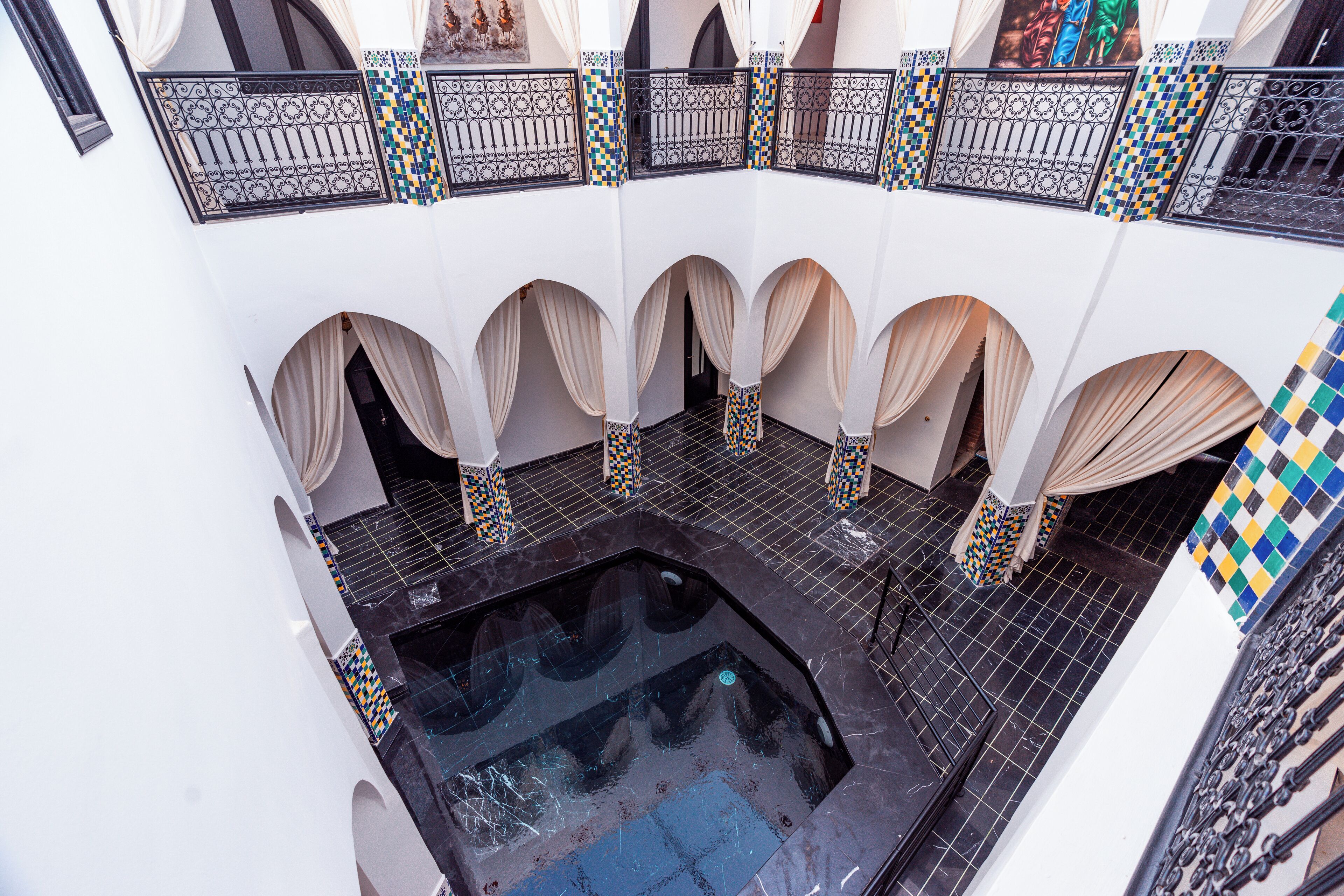 A courtyard with a central pool, white walls, and patterned tiles.