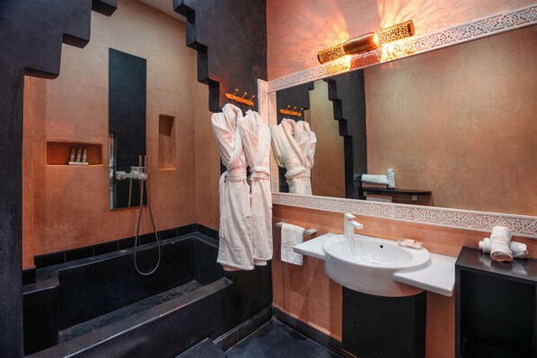 A modern bathroom with a large mirror, a sink, and a bathtub.