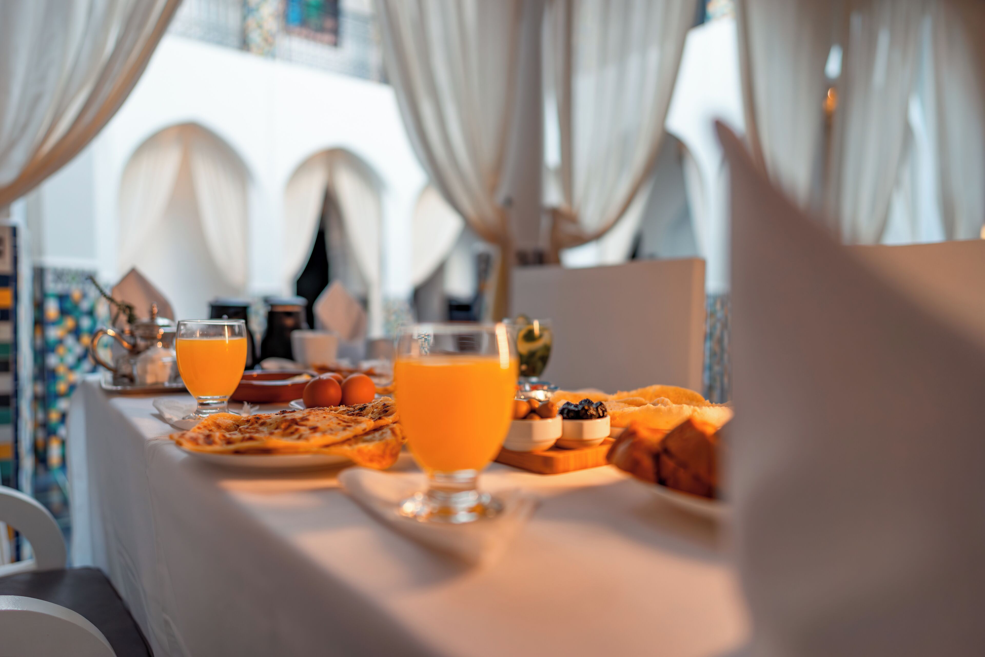 A breakfast table with orange juice, a glass of water, and various breakfast items.