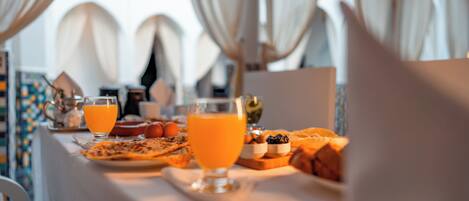 A breakfast table with orange juice, a glass of water, and various breakfast items.