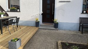 En bygning med en træterrasse, udendørs møbler og blomsterkasser.