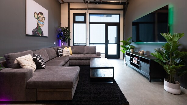 Ein modernes Wohnzimmer mit einer Eckcouch, einem Couchtisch und einem an der Wand befestigten Flachbildfernseher.