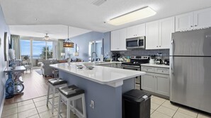A modern kitchen with white cabinets, stainless steel appliances, and a central island with stools.