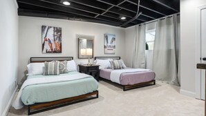 A bedroom with two beds, a nightstand, a mirror, and artwork on the wall.