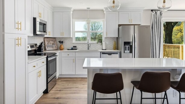 A modern kitchen with white cabinetry, a central island, and pendant lighting.