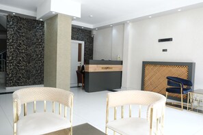A reception area with a reception desk, two chairs, a patterned wall, and a patterned wall behind the desk.