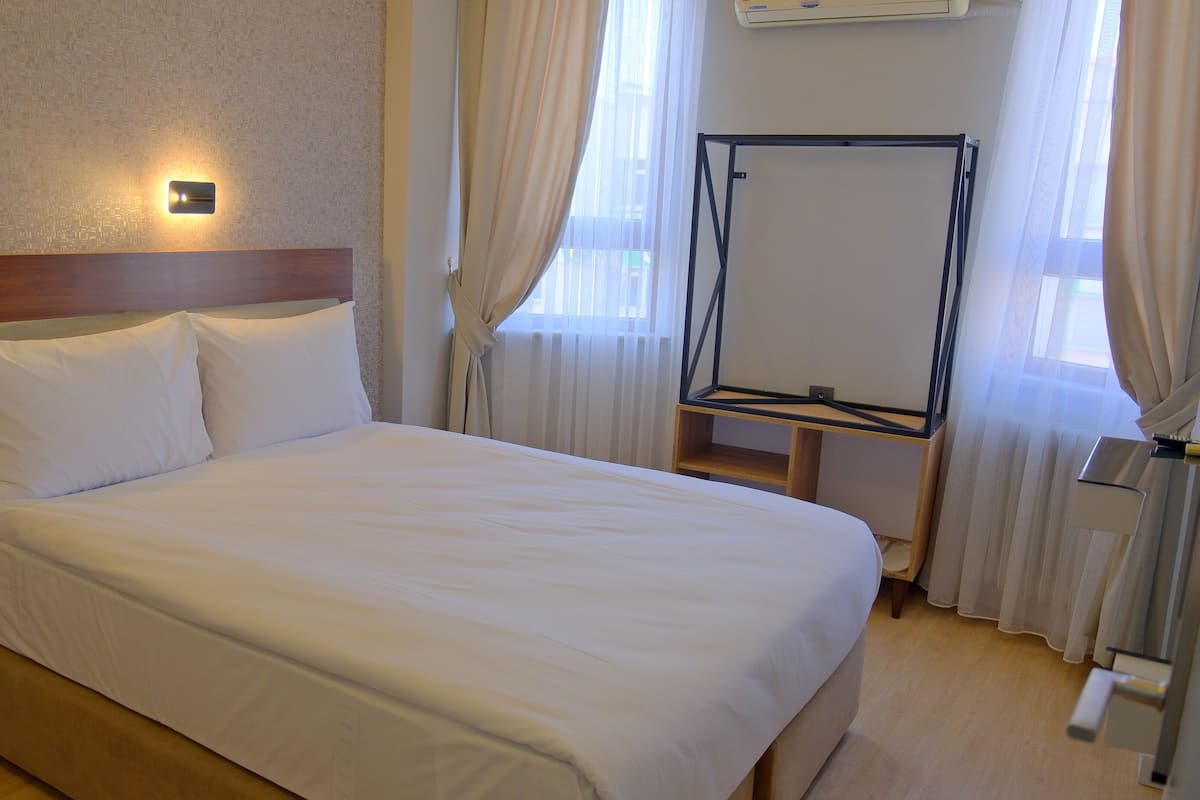 Un lit bien fait, avec du linge de lit blanc, dans une chambre d’hôtel.