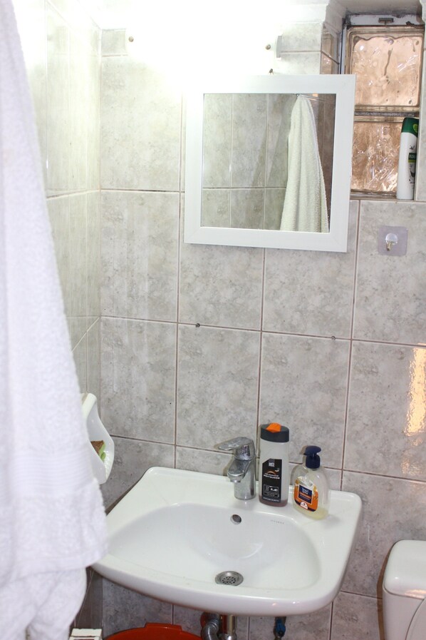 A bathroom with a white sink, mirror, and tiled walls.