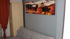 A room with a light-colored sofa, a beige pillow, a wooden cabinet, and a framed picture of a cityscape on the wall. - Remarkable 1-bed Apartment in Thessaloniki (Thessaloniki)