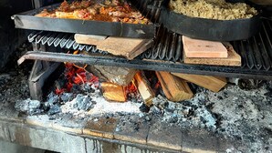A wood-fired oven with two trays of food cooking.