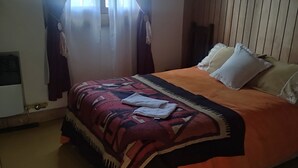 A bedroom with a bed, curtains, a window, and a wooden wall.