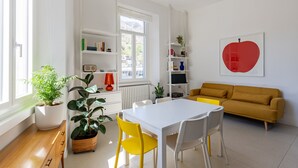 A bright, modern living room with a white table, yellow chairs, a mustard sofa, and a large red heart artwork on the wall. - Lake Design Guest House | Come Center (Como)