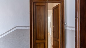 A wooden door leading to a hallway with a light-colored floor and a white wall with a gray border. - Lake Design Guest House | Come Center (Como)