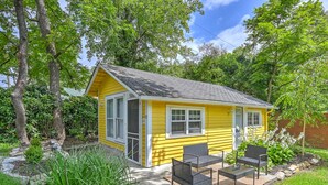 A yellow single-story house with a porch, two chairs, and a table. - Buttercup Cottage close to downtown Hendersonville fully fenced all pets welcome (Hendersonville)