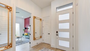 Un pasillo con un tapete estampado, un espejo de marco decorativo y una puerta con paneles de vidrio esmerilado.