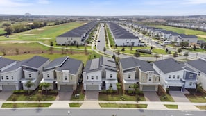 Una zona residencial con casas modernas, un campo de golf y un castillo a lo lejos.