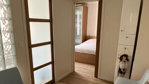 Una habitación con piso de madera, una cama con colcha estampada, un armario y una silla.