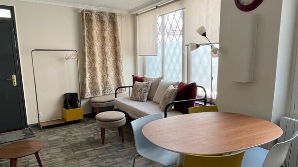 Una sala moderna con un sofá, una mesa redonda de madera y un comedor.