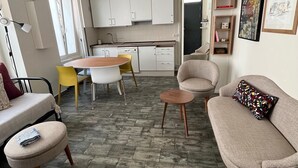 Un espacio habitable compacto con una mesa de comedor, un sofá, una pequeña mesa de centro y una kitchenette.
