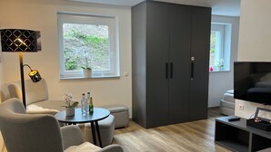 A modern living room with a sofa, a coffee table, a TV, and a wardrobe. - Top Apartment Zentrum Bad Urach 5 Minutes to Train Station (Bad Urach)