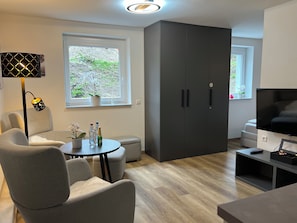 A modern living room with a sofa, a coffee table, a TV, and a wardrobe.