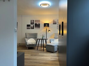 A modern living room with a grey armchair, a small round table, a floor lamp, and a sofa. - Top Apartment Zentrum Bad Urach 5 Minutes to Train Station (Bad Urach)