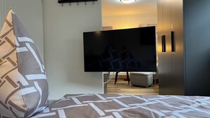 A bedroom with a bed, a flat-screen TV mounted on the wall, a bedside table, and a wardrobe. - Top Apartment Zentrum Bad Urach 5 Minutes to Train Station (Bad Urach)