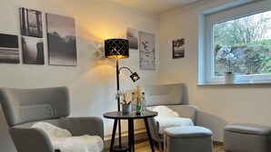 A room with two grey armchairs, a small round table with drinks, a floor lamp, and artwork on the walls. - Top Apartment Zentrum Bad Urach 5 Minutes to Train Station (Bad Urach)