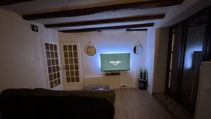Un salon avec un téléviseur diffusant du contenu « Prime Video », une porte, un miroir et une plante.