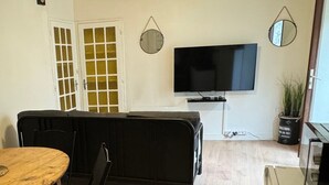 Un salon avec un téléviseur, une table à manger et un canapé.