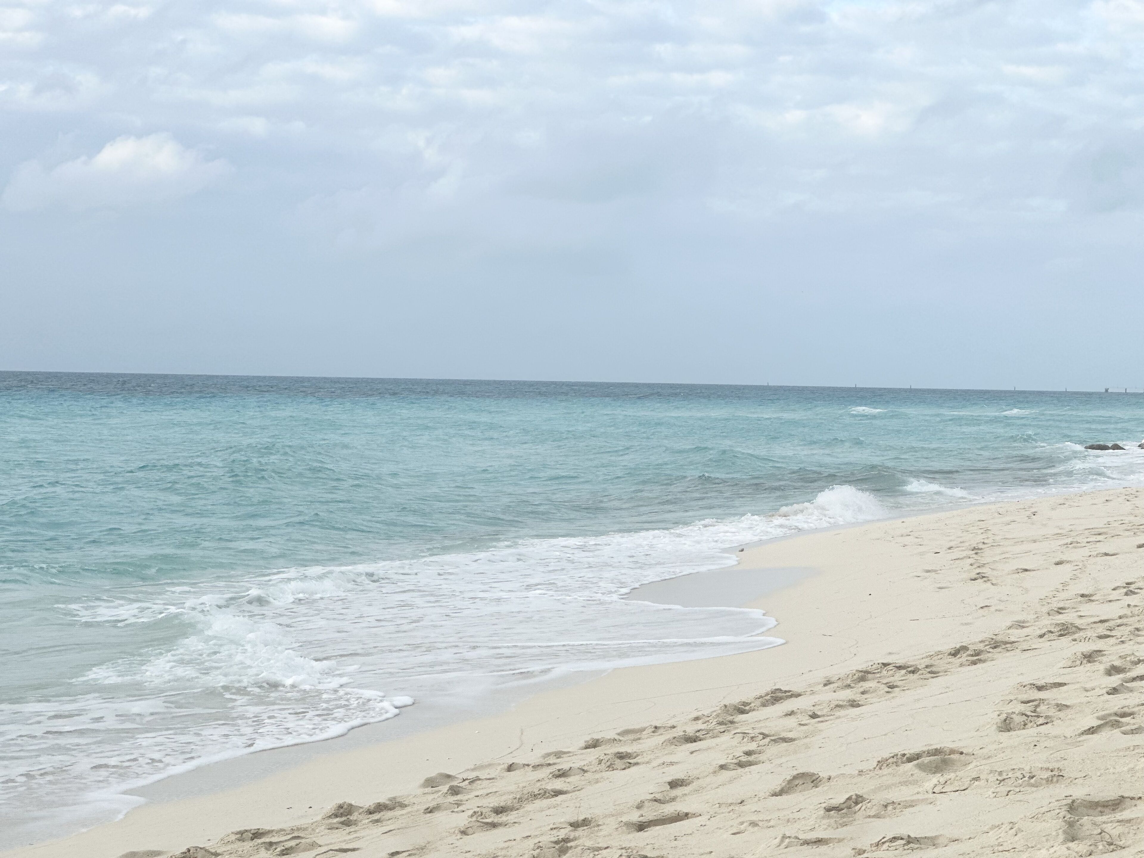 Uma praia com costa arenosa e ondas oceânicas calmas.