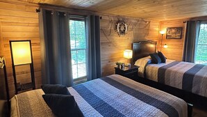 Une chambre confortable, aménagée dans le style d’un chalet, avec deux lits, des murs en bois, un décor représentant un gouvernail de bateau et une fenêtre avec des rideaux.