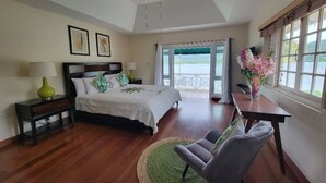 A bedroom with a bed, a chair, a table, a ceiling fan, and a view of the outdoors. - The perfect tropical getaway for couples, families and friends! (Montego Bay)
