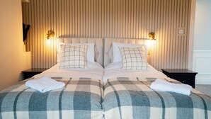 Un lit double avec une couverture à carreaux, deux tables de chevet avec des lampes et un mur à rayures.