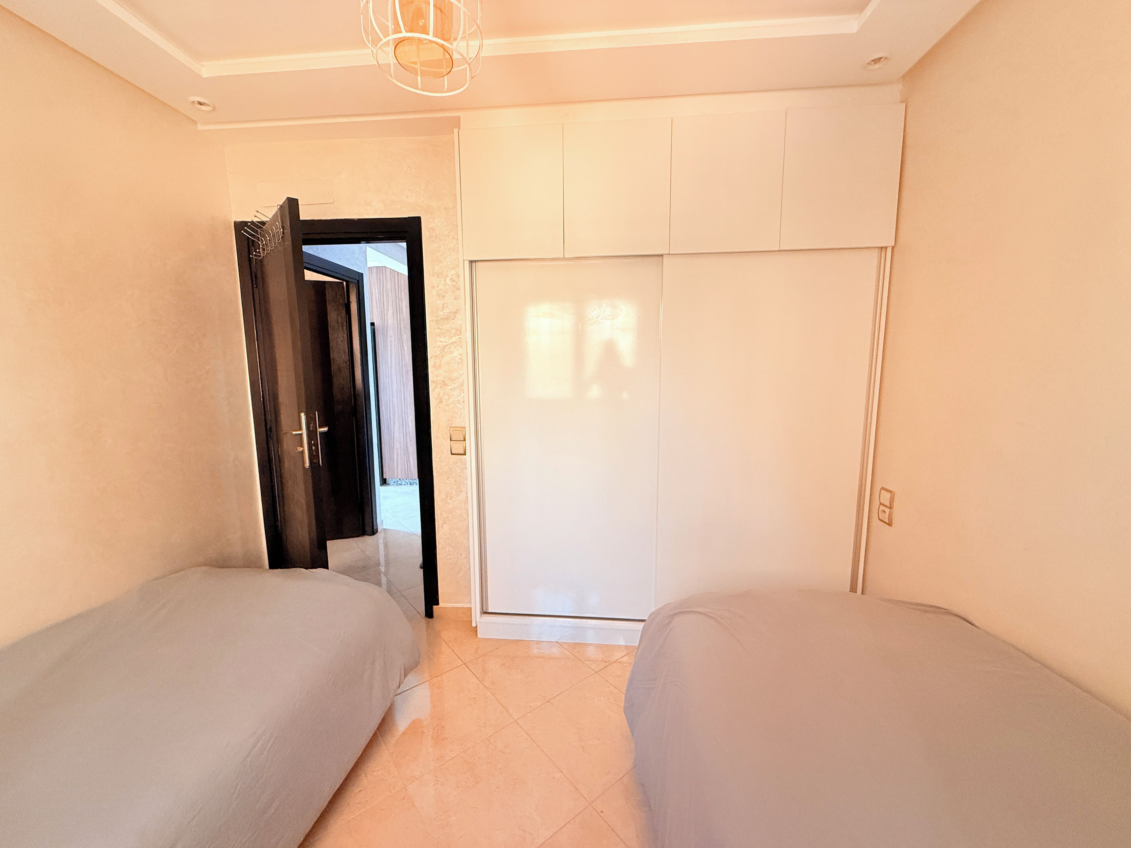 Un dormitorio con dos camas, un armario y una puerta que da a otra habitación.