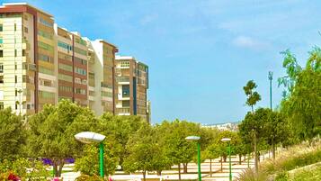 Un edificio residencial de varios pisos con balcones, rodeado de vegetación y faroles.