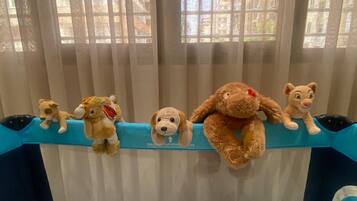 Una cuna con colchón y cabecera azules, con una hilera de peluches.