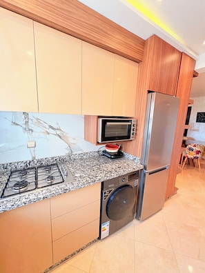 A modern kitchen with a built-in oven, a microwave, a stainless steel refrigerator, a washing machine, and a gas stove. - restaurant, quiet, family, equipped, air-conditioned, parking, 7 people, agadir (Agadir)