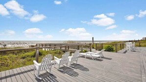 A wooden deck with white Adirondack chairs overlooking a beach. - Spacious 4 Bedroom, 3 Bath Condo in Pawleys Island: 2-minute drive to pvt beach (Pawleys Island)