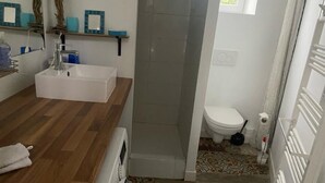 Et badeværelse med hvid vask, trægulv og toilet.