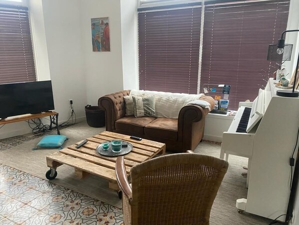 A living room with a sofa, a coffee table, a TV, and a keyboard. - Maison Jardin RDC Proche Plages et Commerces (Trébeurden)