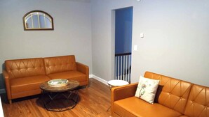 A living room with two brown leather sofas, a round coffee table, and a small side table. - Cozy second floor unit in the heart of Downtown Charlevoix, 1BR / 1BA sleeps 4 
 (Charlevoix)