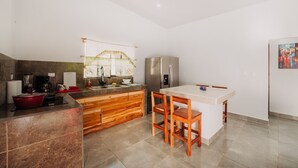 A modern kitchen with a central island, wooden cabinets, and stainless steel appliances. - Mini Oasis in Avellanas beach, natural pool, parking, A/C, kitchen #1 (Tamarindo)